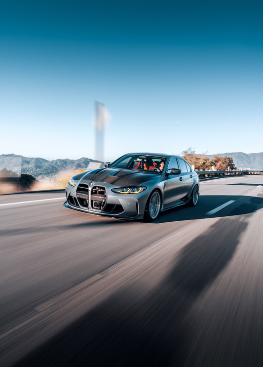 BMW G8X M3 with carbon fiber aero parts driving on a canyon road